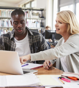 Teen student on laptop with teacher