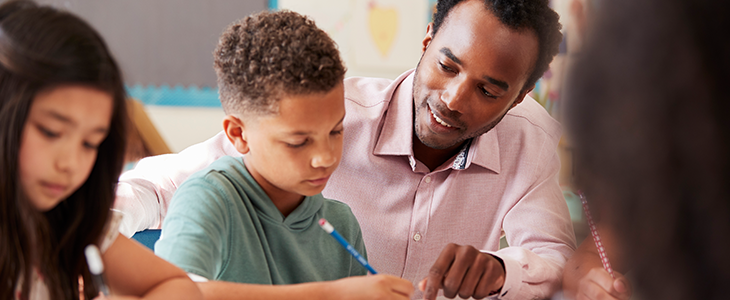 Teacher assisting middle school boy writing