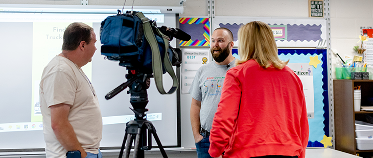 Reporter and cameraman recording interview with teacher