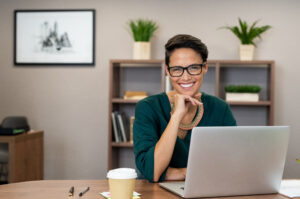 smiling woman sitting in office at laptop computer