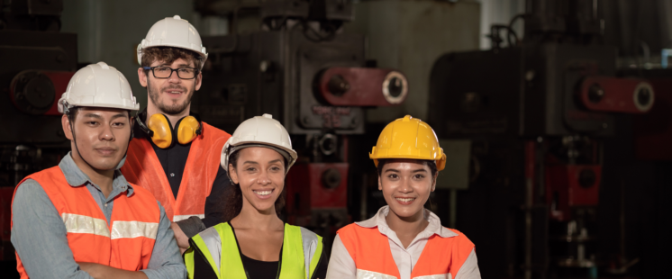 Group of smiling people in safety vests and hard hats.