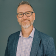Smiling Gregg McGough in button down shirt and blazer